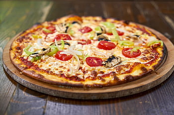 Delicious homemade pizza with fresh vegetables and cheese on a wooden board. HD wallpaper