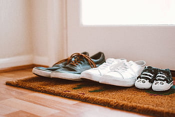 Cozy family shoes on a doormat at home entrance, symbolizing warmth and connection. HD wallpaper