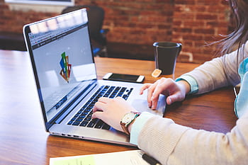 Woman working on design project using laptop at modern workspace indoors. HD wallpaper