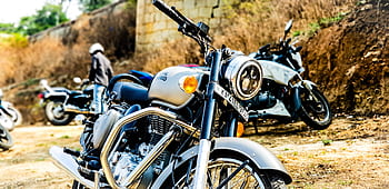 Close-up of a classic motorcycle parked outdoors with other bikes, conveying adventure and dom. HD wallpaper