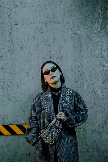 Edgy portrait of a fashionable woman in sunglasses and a chic coat against an urban backdrop. HD phone wallpaper