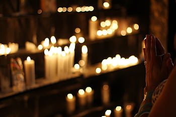 Hands clasped in prayer by candlelight in a church in São Paulo, Brazil, evoking a spiritual atmosphere. HD wallpaper