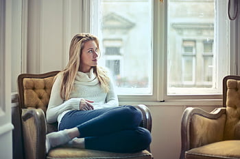 A serene moment of a woman in a cozy room, enjoying leisure time by the window. HD wallpaper