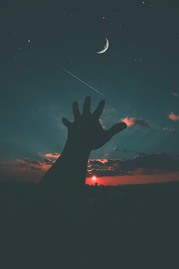 Silhouette of a hand reaching towards the crescent moon and stars in a dramatic dusk sky. HD phone wallpaper