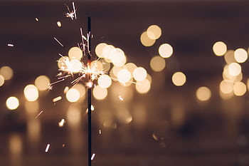 Close-up of a vibrant sparkler with a bokeh background, perfect for festive themes. HD wallpaper