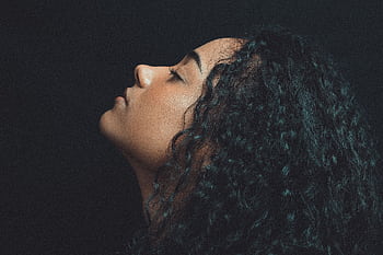 Artistic side profile portrait of a woman with curly hair in dramatic lighting. HD wallpaper