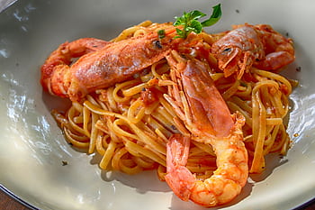 Close-up of a flavorful seafood pasta dish with king prawns, perfectly cooked with Italian flavors. HD wallpaper