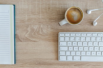 Flat lay of a workspace featuring coffee, a keyboard, and a notebook on a wooden desk. HD wallpaper