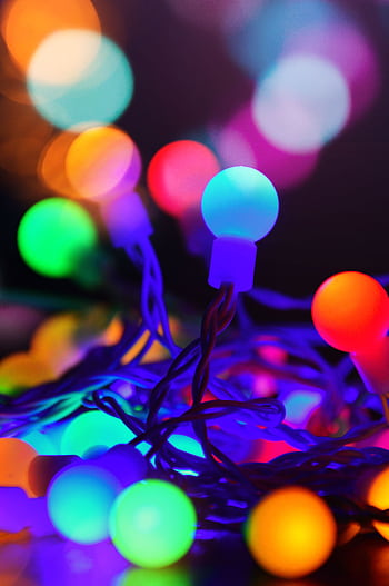 A close-up of colorful glowing Christmas string lights with a bokeh effect, perfect for festive celebrations. HD phone wallpaper
