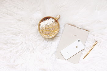 Minimalist flat lay of coffee, smart, notebook, and pen on white fur. HD wallpaper