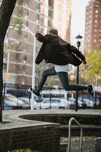 Man performing a parkour jump in an urban environment, capturing agility and dom. HD phone wallpaper