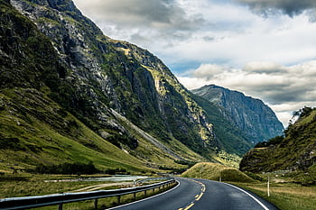 Curving highway through a dramatic Norwegian fjord landscape, perfect for travel enthusiasts. HD wallpaper