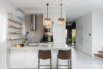 Beautifully designed modern kitchen with white cabinets and marble accents, featuring elegant lighting and a clean workspace. HD wallpaper