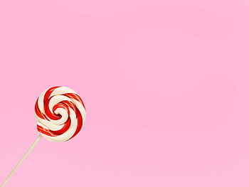 Vibrant red and white lollipop on a pastel pink background, perfect for confectionery themes. HD wallpaper