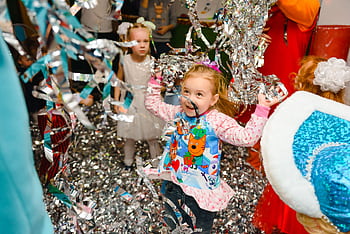 Joyful children having fun at an indoor party, with colorful streamers adding to the festive atmosphere. HD wallpaper