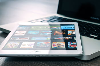Tablet displaying streaming services on a laptop, illustrating digital entertainment setup. HD wallpaper