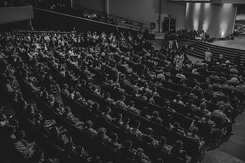 Monochrome of a large audience seated in a theater auditorium from a high angle. HD wallpaper