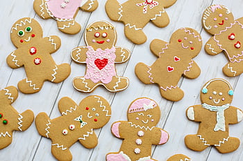 A delightful assortment of decorated gingerbread cookies on a wooden table, perfect for the holiday season. HD wallpaper