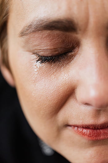 Close-up portrait of a woman shedding a tear, expressing deep sadness. HD phone wallpaper