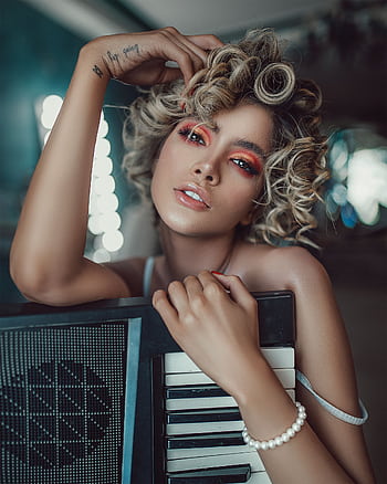 A fashionable woman poses with a keyboard, showcasing modern style and charisma in an indoor setting. HD phone wallpaper