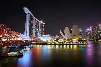 Stunning night view of Marina Bay Sands and Helix Bridge illuminated over water in Singapore. HD wallpaper