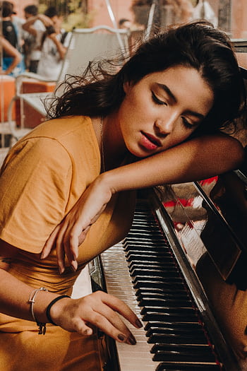 A woman peacefully resting on piano keys, symbolizing musical tranquility indoors. HD phone wallpaper
