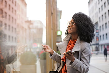 Happy woman with curly hair shopping in the city, reflecting joy and a trendy lifestyle. HD wallpaper
