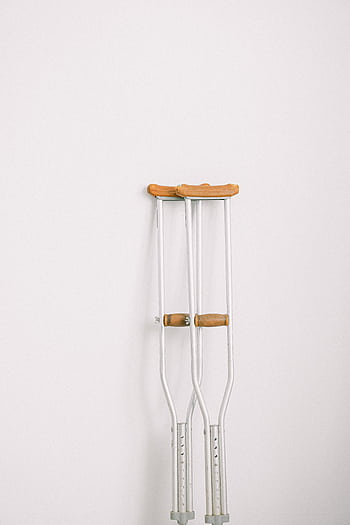 Minimalist of crutches leaning on a white wall indoors. HD phone wallpaper