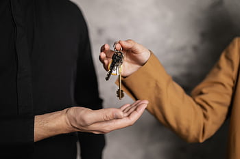 Detailed close-up of one person handing over keys to another, symbolizing a real estate transaction. HD wallpaper