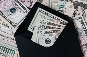 Close-up of US dollar bills in an open black envelope, symbolizing cash savings. HD wallpaper
