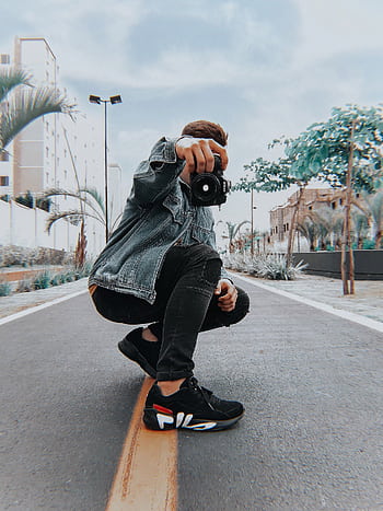 A male model stylishly poses with a camera on a city street in an urban setting. HD phone wallpaper