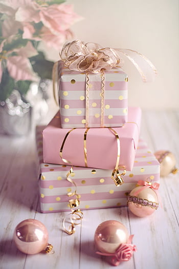 Charming Christmas presents wrapped in pink and gold with festive ornaments on a wooden table. HD phone wallpaper