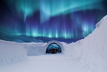 Captivating northern lights illuminate a snowy igloo in the Arctic landscape at night. HD wallpaper