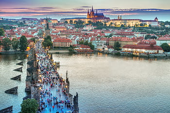 A vibrant view of Charles Bridge leading to Prague Castle at sunset. HD wallpaper