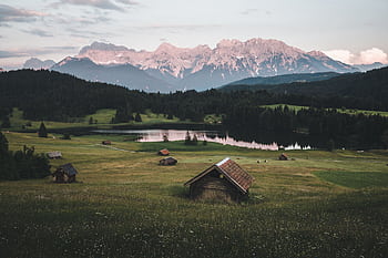 Explore the serene Bavarian landscape in Krün, Germany, with lush fields, a tranquil lake, and majestic mountains at dawn. HD wallpaper