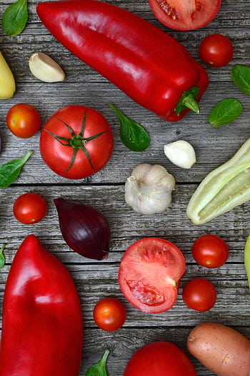 Vibrant fresh vegetables including tomatoes, peppers, and garlic on a rustic wooden surface. HD phone wallpaper