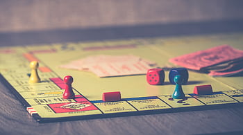 A close-up of a Monopoly board game with pieces and dice scattered around. HD wallpaper