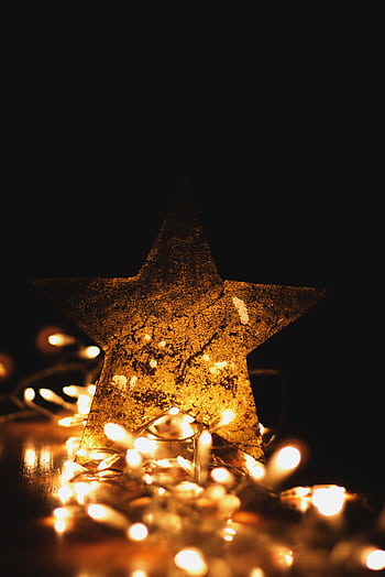 A shimmering golden star surrounded by warm Christmas string lights on a dark background. Perfect for holiday themes. HD phone wallpaper