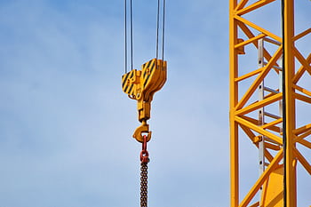 Close-up of a yellow crane arm against a clear blue sky, showcasing industrial equipment. HD wallpaper