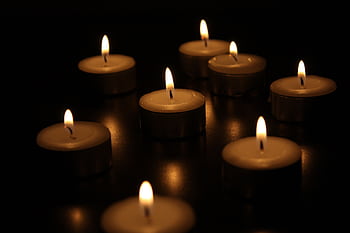 A serene arrangement of burning candles casting a warm glow in the dark. HD wallpaper