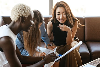A diverse group of women engage in a collaborative business meeting in an office setting. HD wallpaper