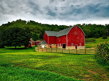 Vibrant red barn amidst lush greenery and cloudy skies in Wisconsin. HD wallpaper