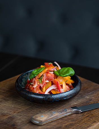 Fresh vegetable salad with colorful peppers and onions in a black bowl on a wooden board. HD phone wallpaper