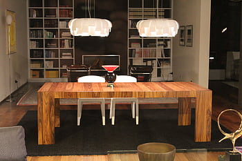 Luxurious living room featuring a modern wooden table under stylish pendant lights. HD wallpaper