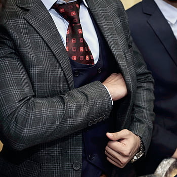 Close-up of a man in a designer suit, adjusting his tie, showcasing business fashion. HD phone wallpaper
