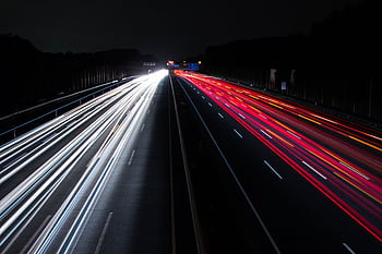 Long exposure of colorful light trails on a highway, capturing the night motion. HD wallpaper