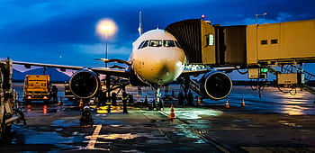 A commercial airplane on the runway at Bengaluru airport during night with a blue sky backdrop. HD wallpaper