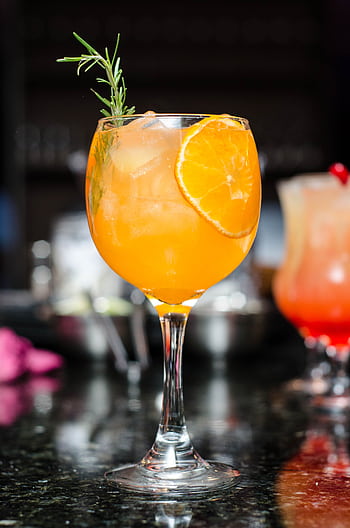 Refreshing orange cocktail with ice, garnished with rosemary and orange slice. Perfect for summer parties. HD phone wallpaper