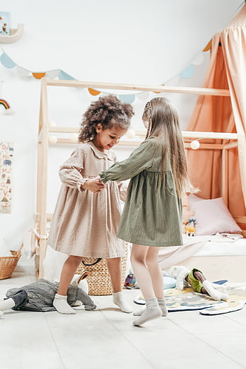 Two young girls enjoy dancing together in a cozy playroom, embodying childhood friendship and joy. HD phone wallpaper