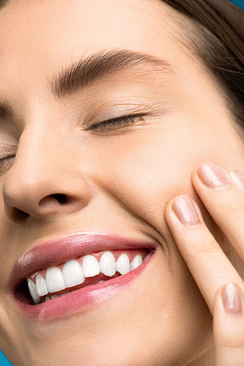 A close-up portrait of a joyful woman with closed eyes, pink lipstick, and her hand touching her cheek. HD phone wallpaper